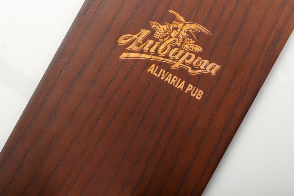 Alivaria Pub menu cover — dark walnut wood, laser logo engraving, close-up