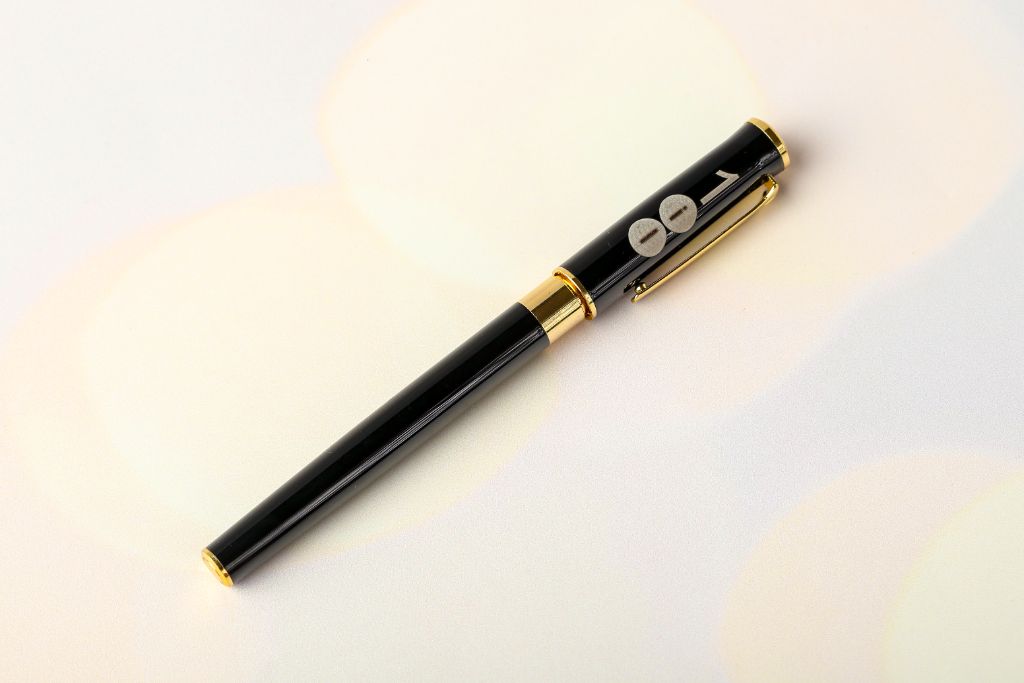 Black metal rollerball pen with gold details — full view with cap on