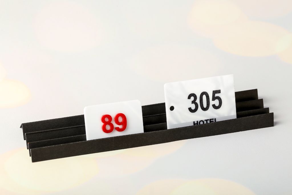 Hotel room number plates — white acrylic, red and black numerals 89 and 305, hanging style