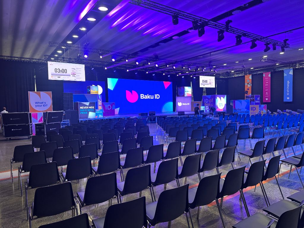 Baku ID 2024 main hall — LED stage, truss lighting rig, branded columns and full seating for 1000+ guests