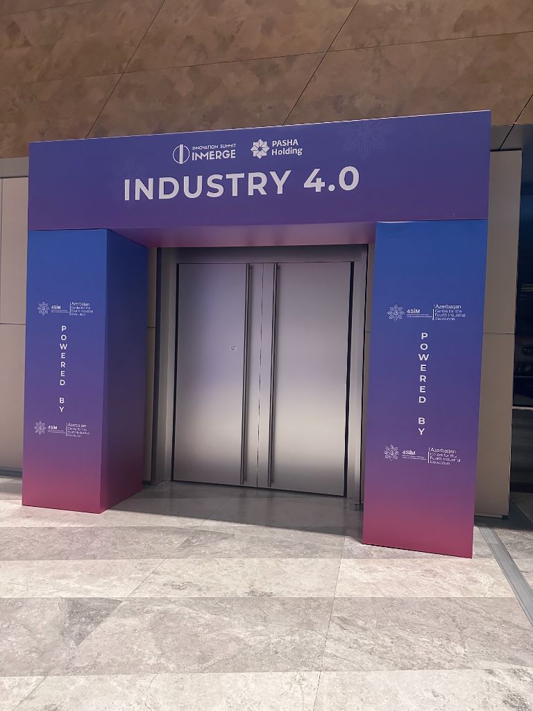 INMerge 2024 INDUSTRY 4.0 stage entrance arch — powered by 4SIM, blue-purple gradient