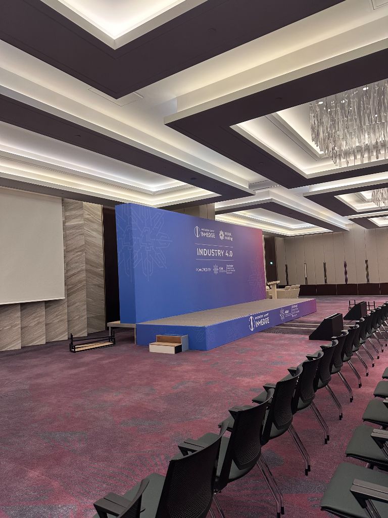 INMerge 2024 Industry 4.0 stage interior — blue backdrop, stage platform, seating ready