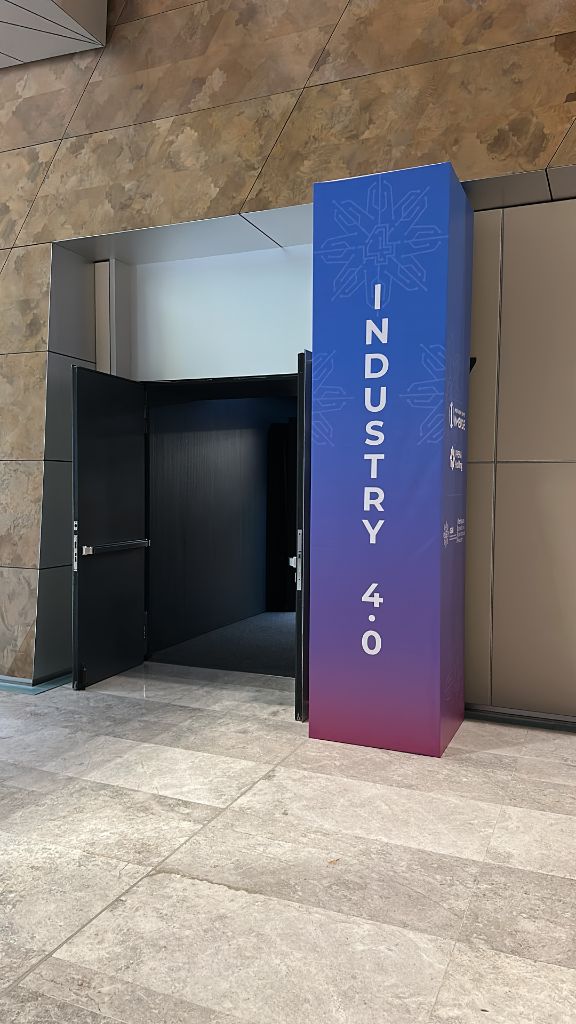 INMerge 2024 Industry 4.0 stage pillar totem — blue purple gradient with 4SIM branding